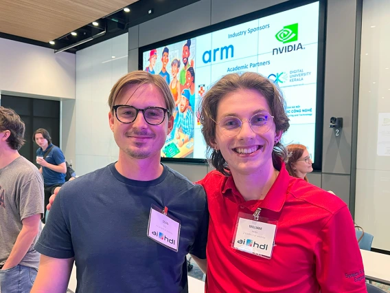 A man in a grey shirt poses for a photo with a man in a red shirt.