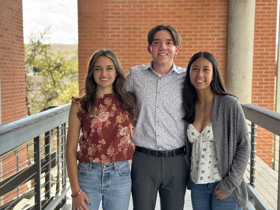 Two women and a man with brown hair pose for a photo.
