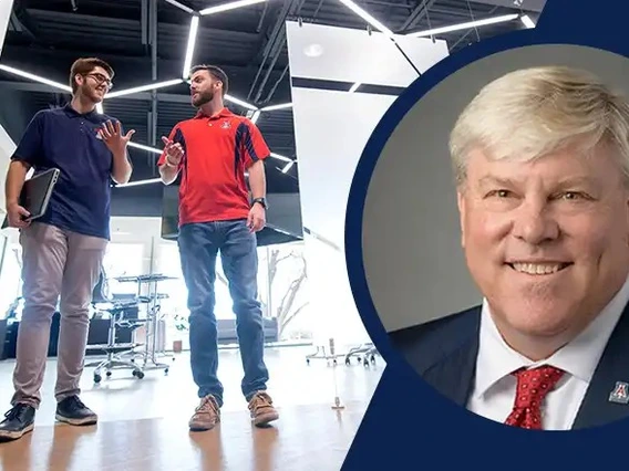 Two students talk in a bright hallway.