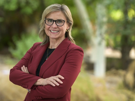 A woman with blond hair wears a red suit jacket.