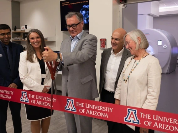 People in suits cut a red ribbon.