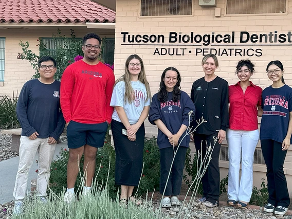 Students and a dentist take a photo outside of a dental office.