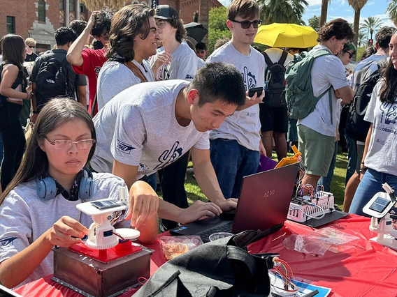 Students crowd around self-made solar trackers.