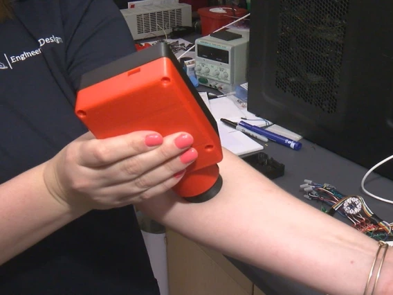 Close up of a woman holding a plastic device onto her left arm.