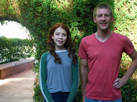 Two people standing in front of an ivy-covered archway on the UA campus.