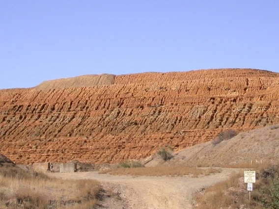 A pile of mine tailings against a blue sky.