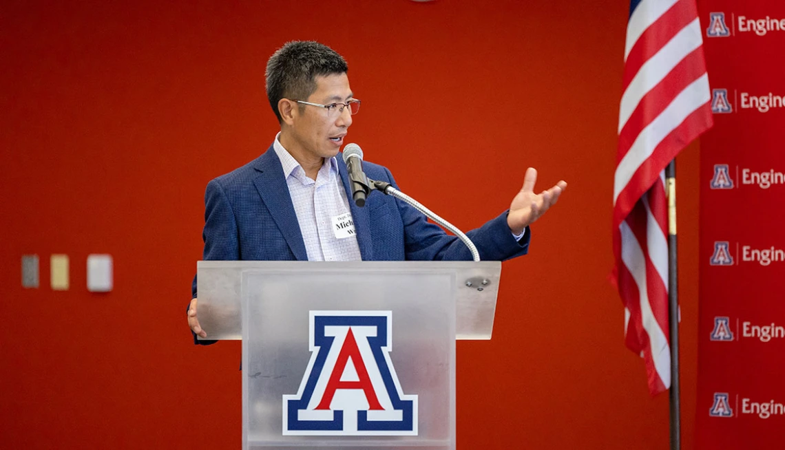 Michael Wu makes a speech at a podium with the University of Arizona logo.