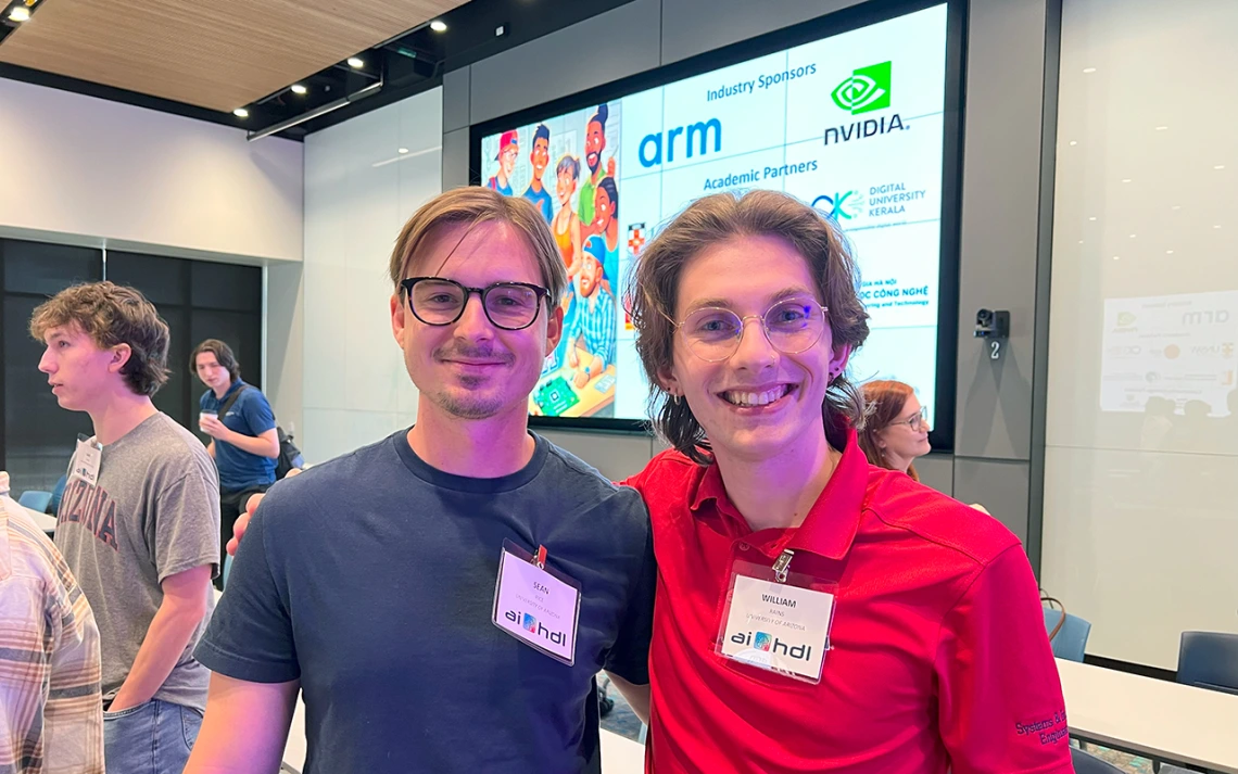 A man in a grey shirt poses for a photo with a man in a red shirt.