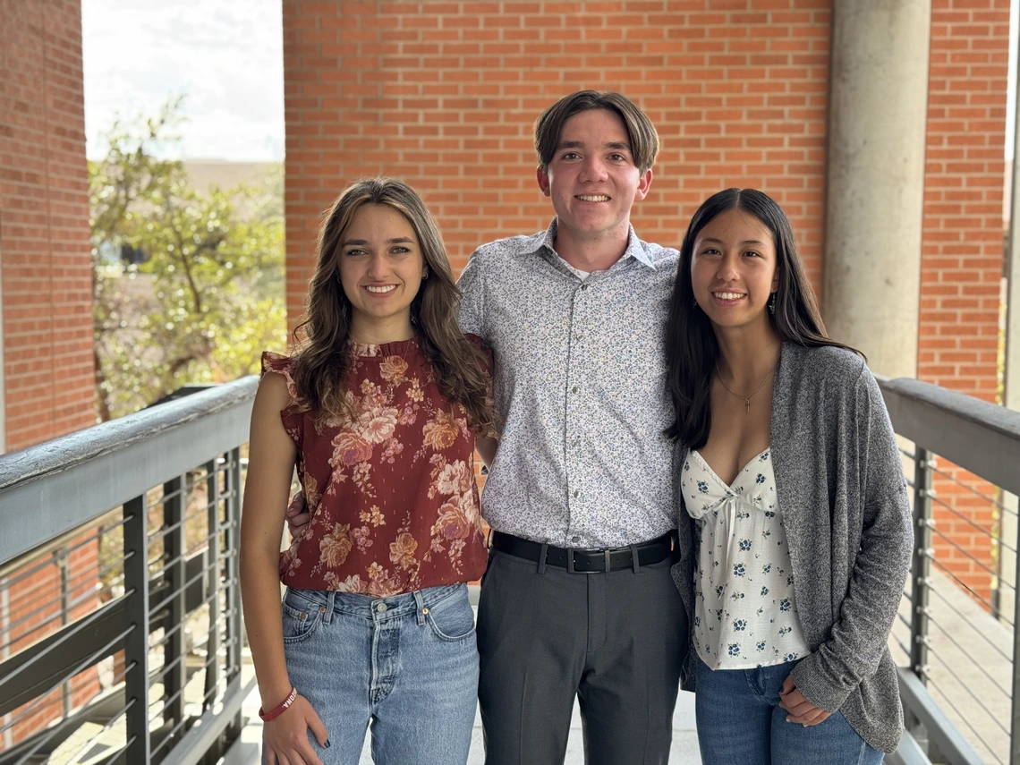 Two women and a man with brown hair pose for a photo.