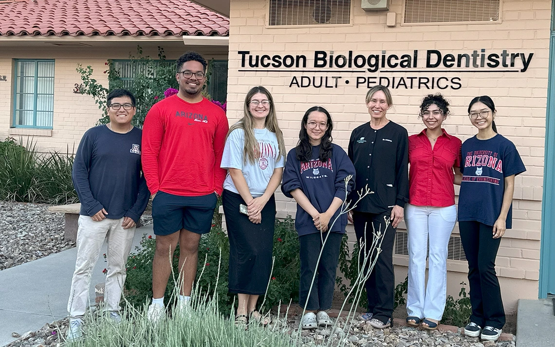 Students and a dentist take a photo outside of a dental office.