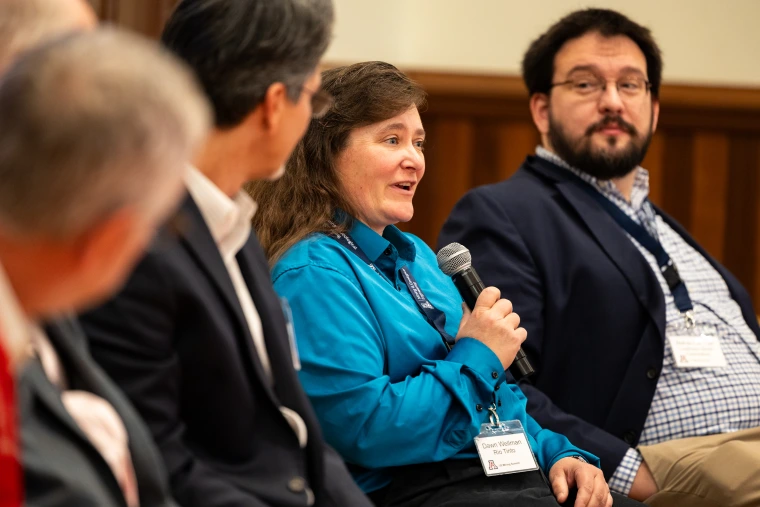 Three fellow panelists listen to Dawn Wellman, speaking with a microphone.