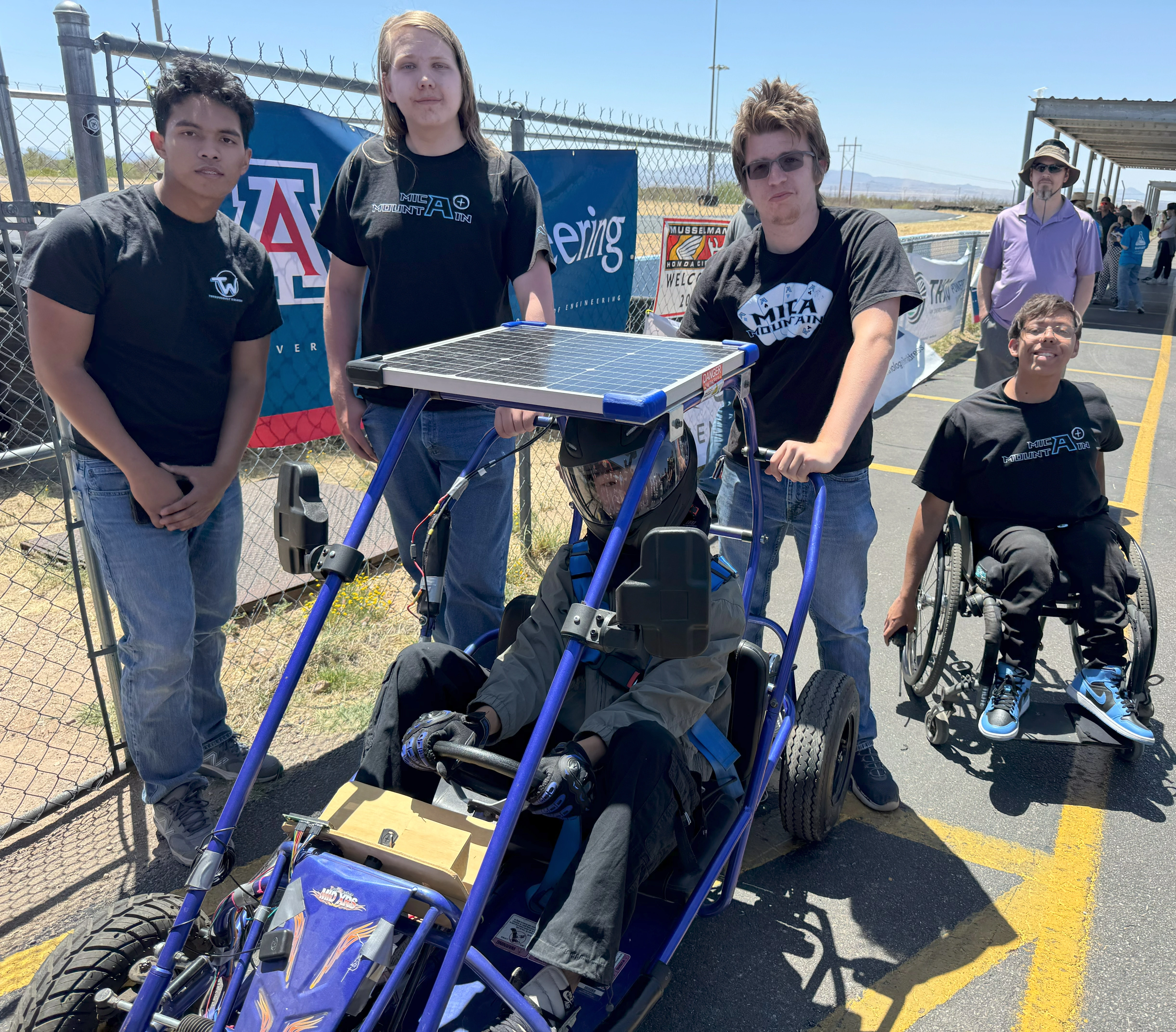 Four students gather around a go-kart.