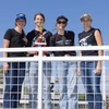 Four high school students pose outdoors with a trophy.