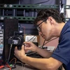 A man in blue shirt looks a microscope. 