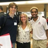 Three students smile for a photo in a large ballroom.