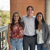 Two women and a man with brown hair pose for a photo.