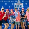 Six adults in multicolored shirts stand in front of a U of A College of Engineering photo wall.