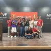 A group of students pose for a photo on a large stage.